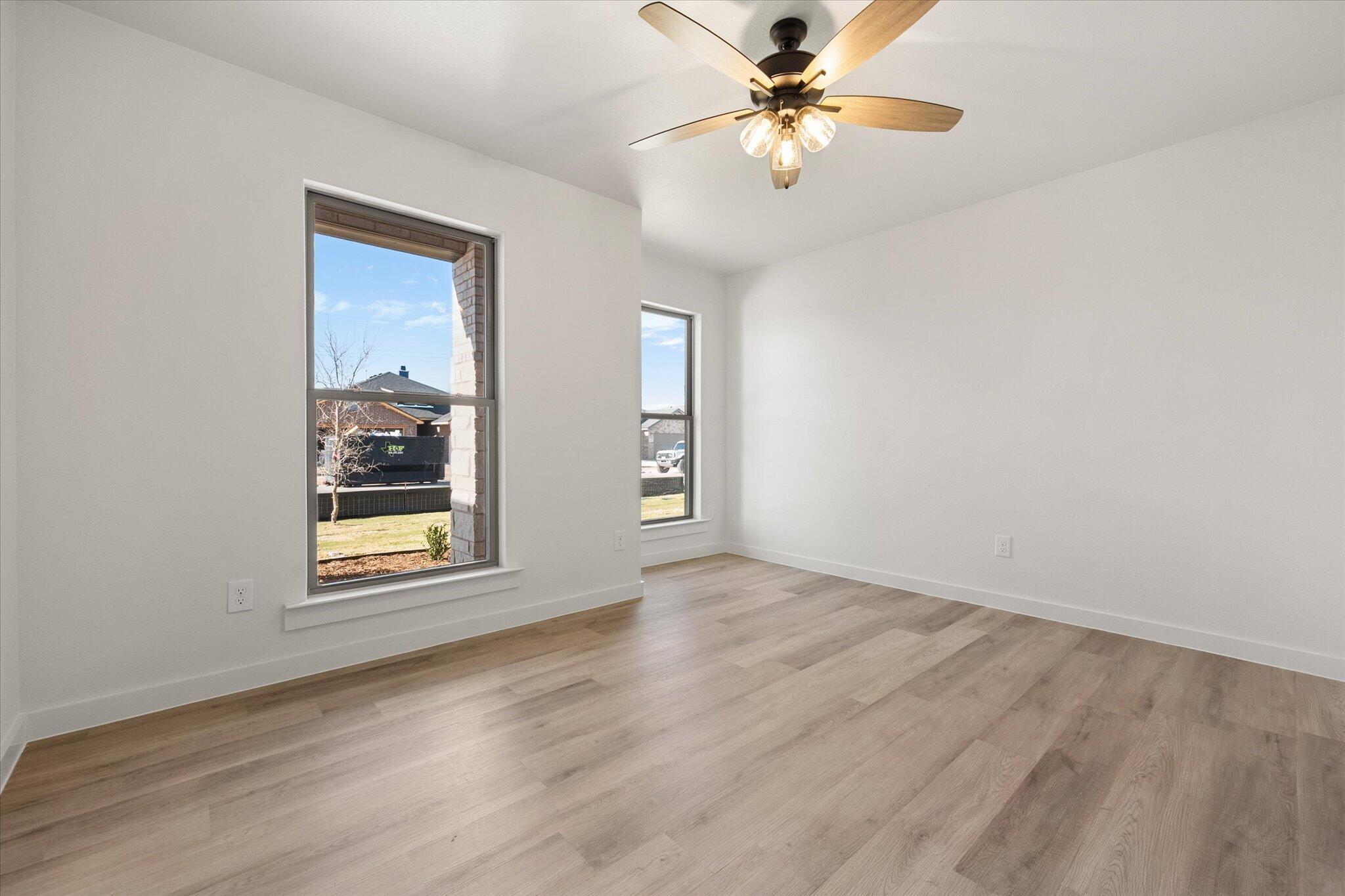 6925 53rd Street Lubbock, TX 79407 - Photo 20 of 22 an empty room with wooden floor chandelier fan and windows