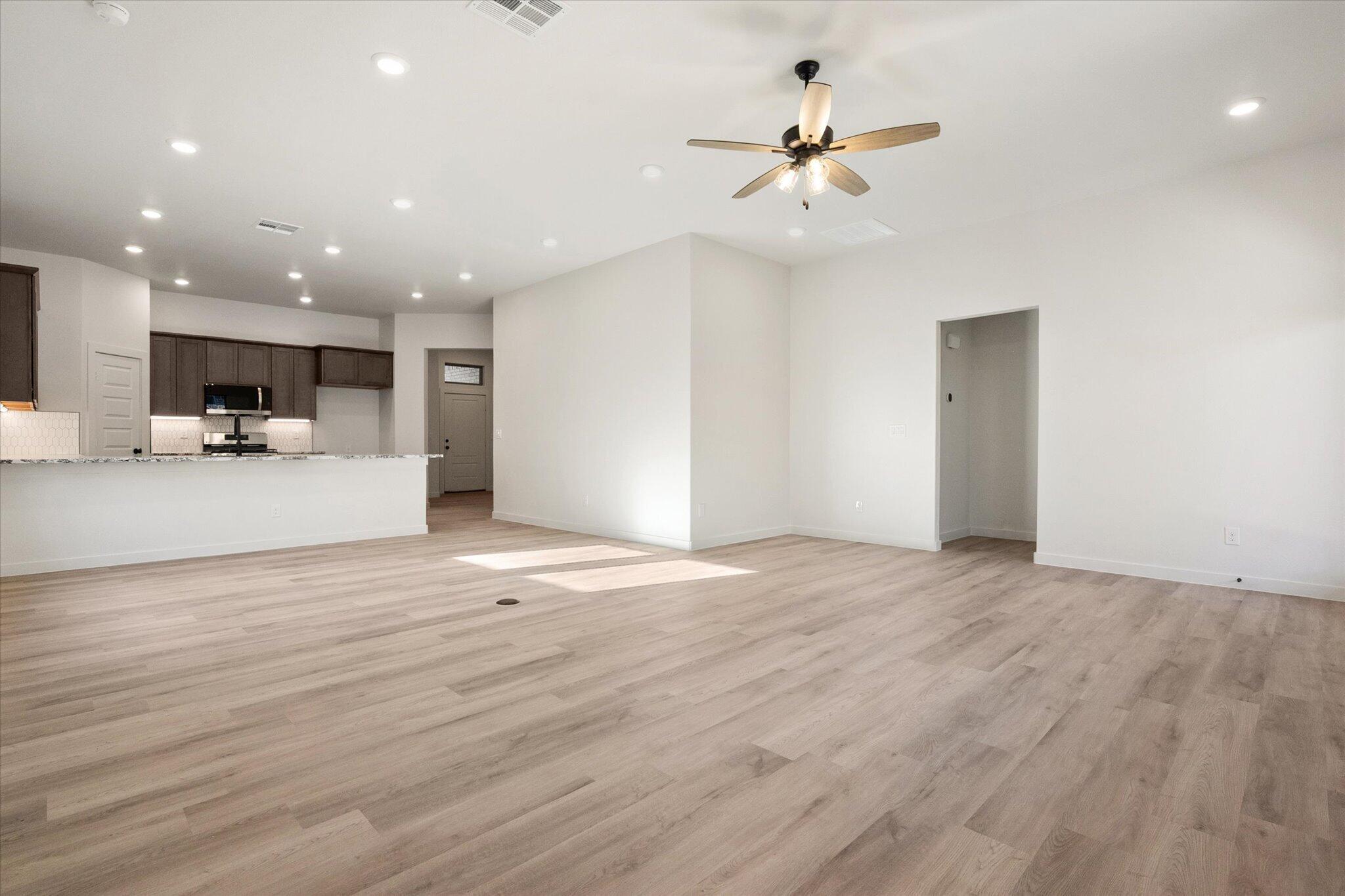 6925 53rd Street Lubbock, TX 79407 - Photo 4 of 22 a view of a livingroom with kitchen island stainless steel appliances cabinets and wooden floor