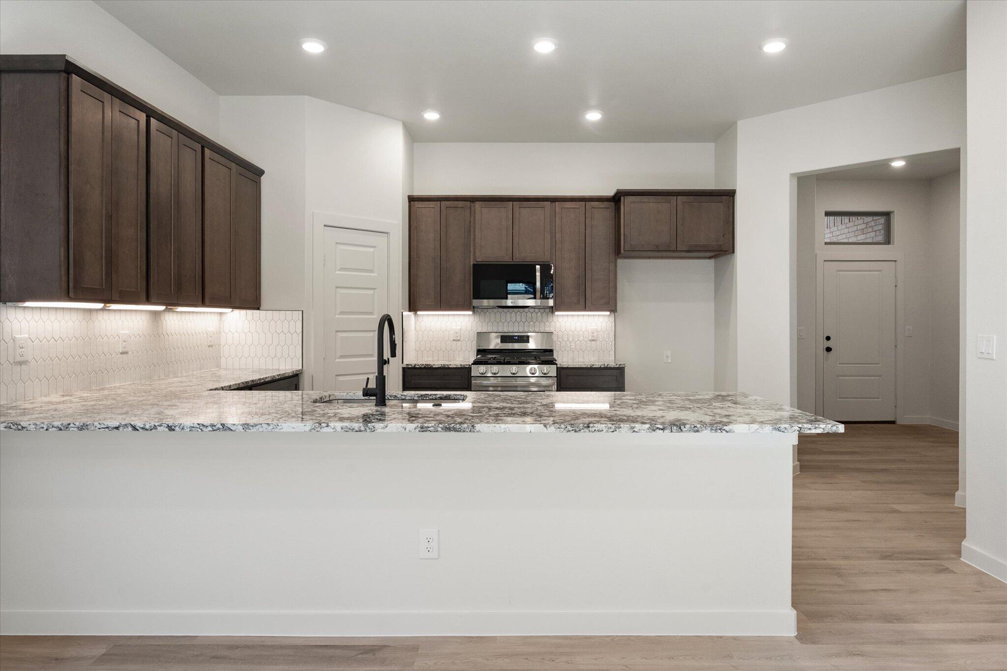 6925 53rd Street Lubbock, TX 79407 - Photo 7 of 22 a kitchen with kitchen island granite countertop a stove and a refrigerator