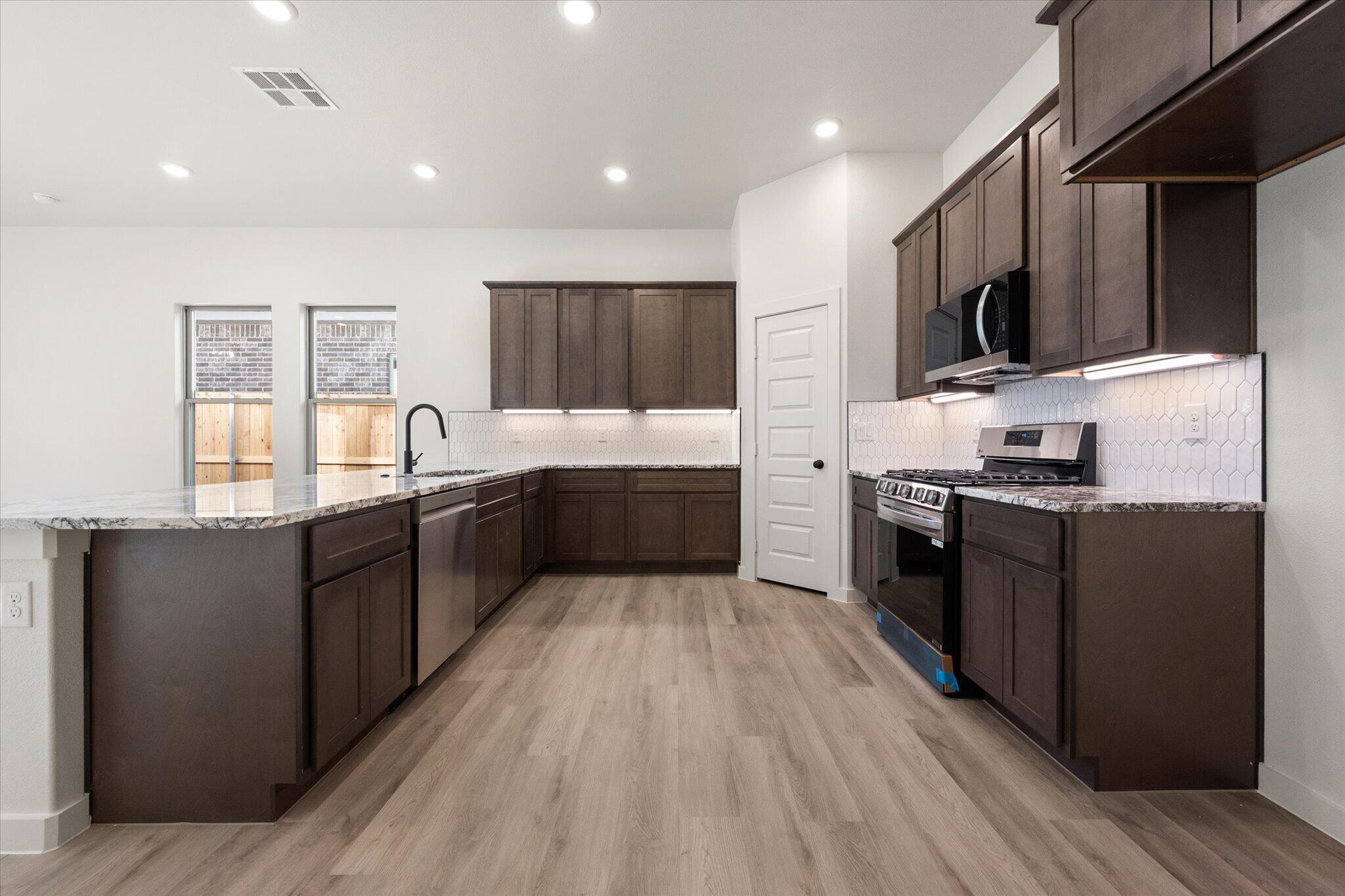 6925 53rd Street Lubbock, TX 79407 - Photo 8 of 22 a large kitchen with stainless steel appliances wooden cabinets a stove and a sink
