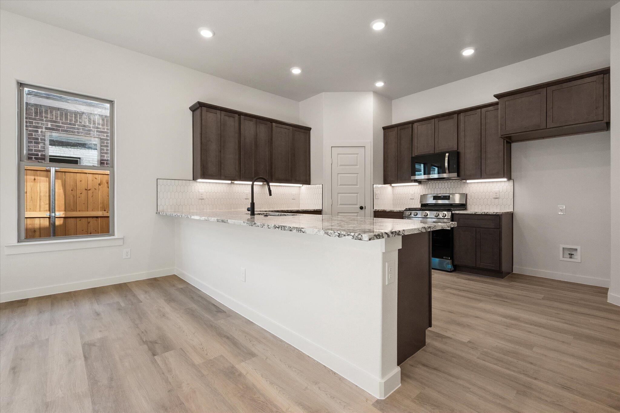 6925 53rd Street Lubbock, TX 79407 - Photo 9 of 22 a kitchen with stainless steel appliances kitchen island granite countertop a stove a sink and a refrigerator