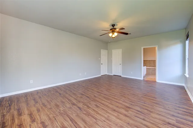 a view of empty room with wooden floor and ceiling fan