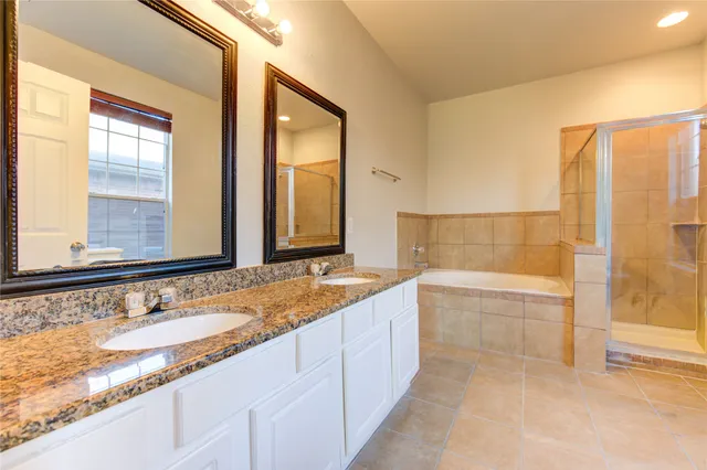 a bathroom with a granite countertop tub sink and mirror