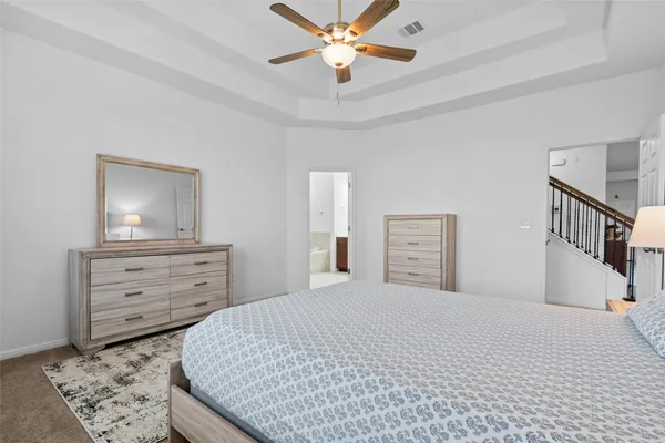 a bedroom with a bed a chandelier and a dresser