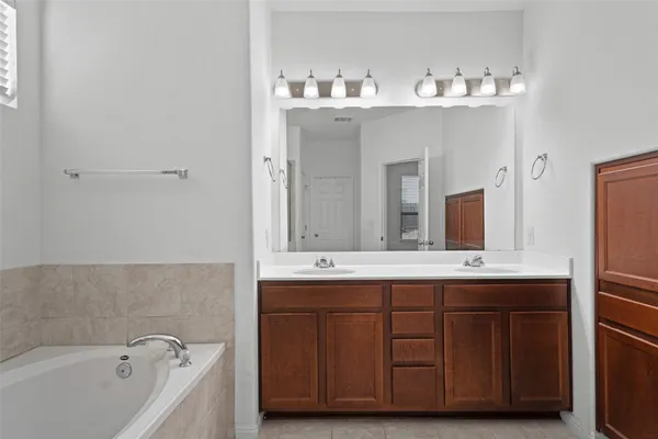 a bathroom with a double vanity sink mirror and bathtub