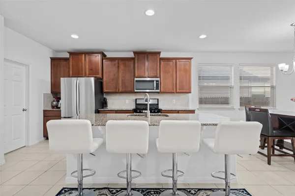 a kitchen with stainless steel appliances granite countertop a refrigerator a stove a dining table and chairs with wooden floor