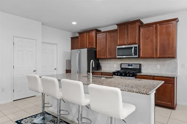 a kitchen with stainless steel appliances granite countertop a stove a sink a microwave a refrigerator and cabinets