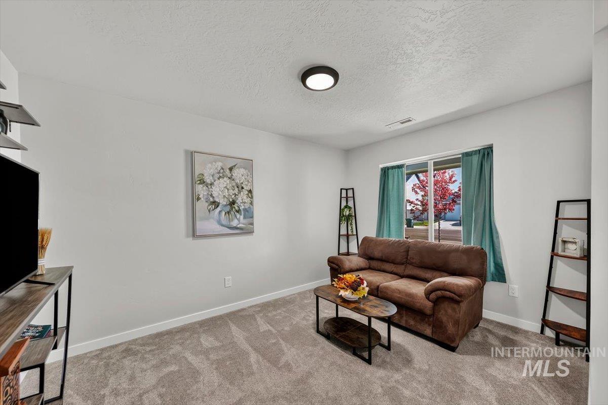 8575 South Foraker Way Kuna, ID 83634 - Photo 4 of 43 Carpeted flooring, light neutral wall paint, and a built-in overhead light fixture