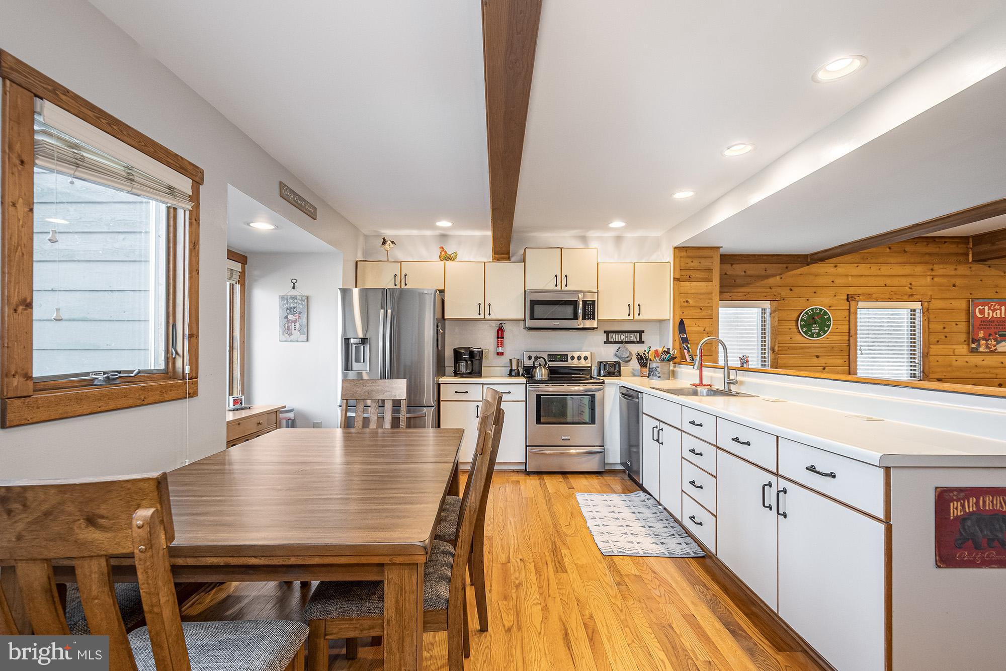 12 Winding Way, Unit 18A McHenry, MD 21541 - Photo 6 of 35 a kitchen with stainless steel appliances kitchen island granite countertop a stove top oven a sink dishwasher a dining table and chairs with wooden floor
