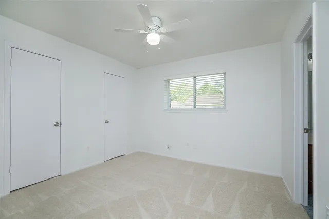 an empty room with windows and ceiling fan
