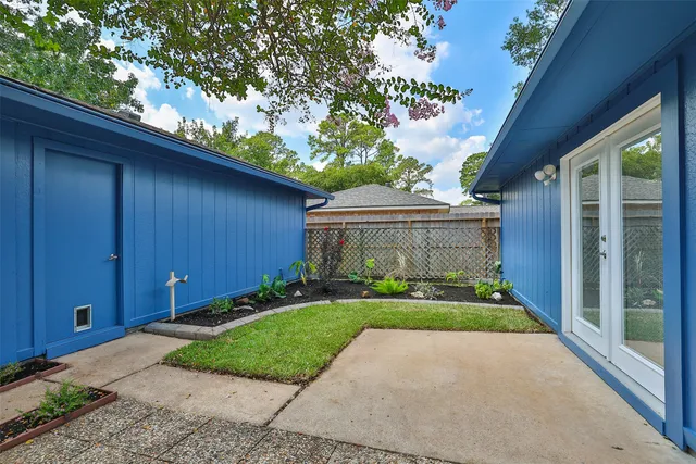 a view of a house with a yard plants and large tree