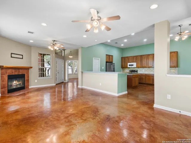 an empty room with windows and chandelier fan