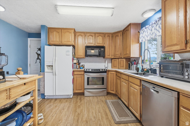 1095 Park Avenue Logan, UT 84321 - Photo 5 of 27 Kitchen with light countertops, stainless steel appliances, light wood-style floors, a textured ceiling, and wood finish cabinets