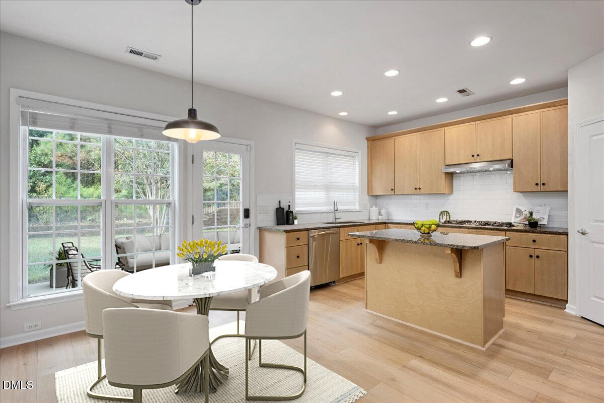 411 Amiable Loop Cary, NC 27519 - Photo 13 of 40 a kitchen with a dining table chairs and white cabinets