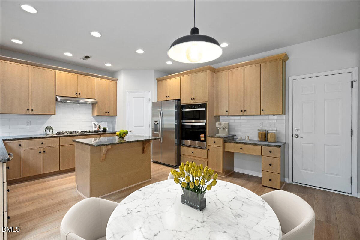 411 Amiable Loop Cary, NC 27519 - Photo 15 of 40 a kitchen with stainless steel appliances granite countertop a stove a sink a microwave a dining table and chairs