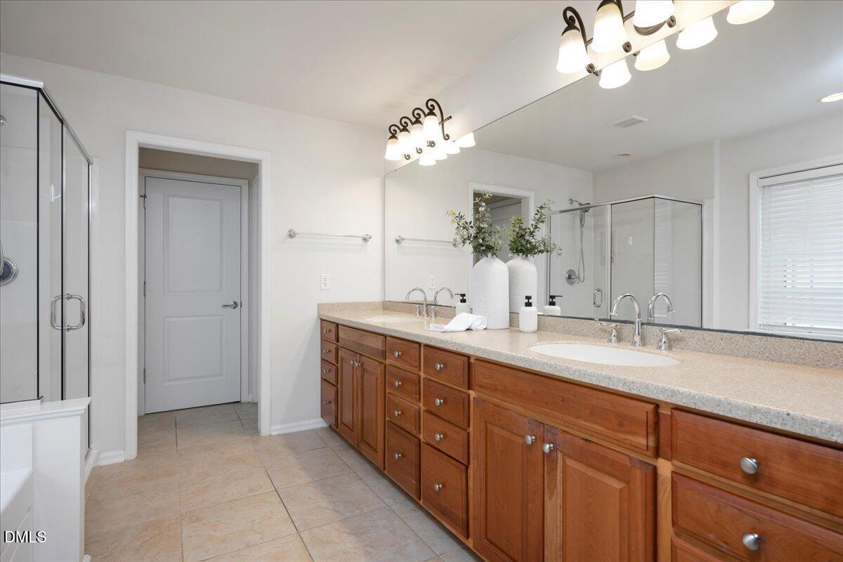 411 Amiable Loop Cary, NC 27519 - Photo 20 of 40 a bathroom with a double vanity sink and a mirror