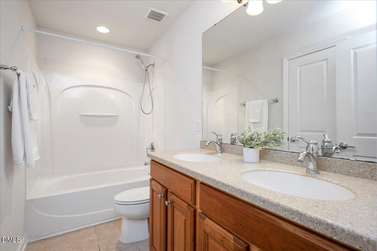 411 Amiable Loop Cary, NC 27519 - Photo 27 of 40 a bathroom with a granite countertop sink toilet and shower