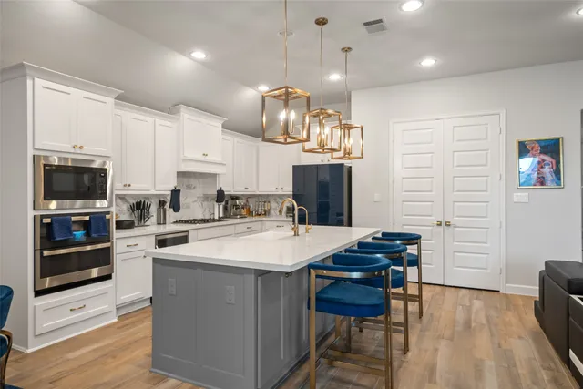 a large kitchen with stainless steel appliances kitchen island granite countertop a stove a sink a refrigerator and a dining table with wooden floor