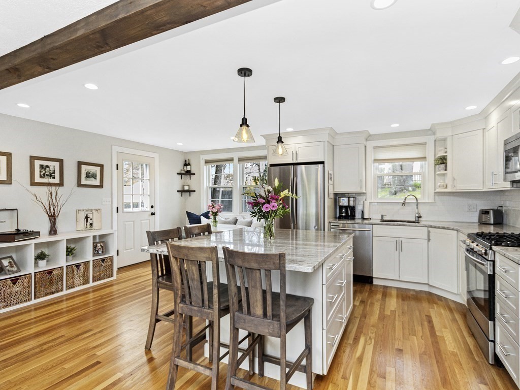 314 Florence Road Waltham, MA 02453 - Photo 4 of 40 a kitchen with stainless steel appliances granite countertop a stove top oven a dining table and chairs with wooden floor