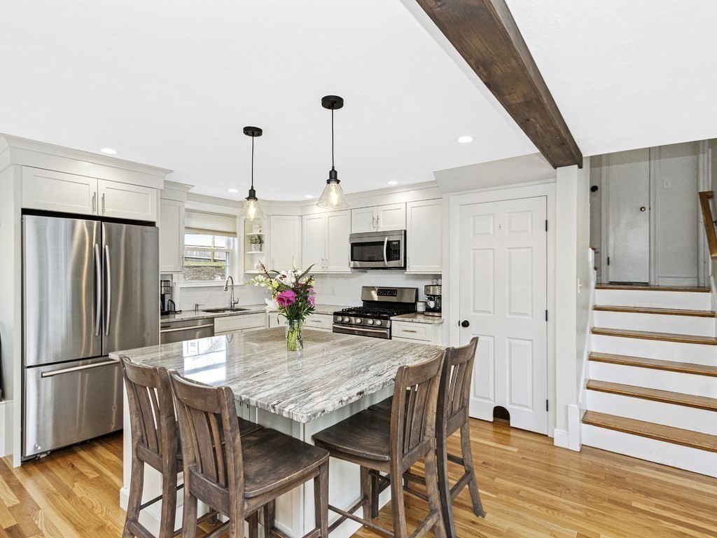 314 Florence Road Waltham, MA 02453 - Photo 7 of 40 a kitchen with stainless steel appliances granite countertop a kitchen island a stove a refrigerator a dining table and chairs with wooden floor