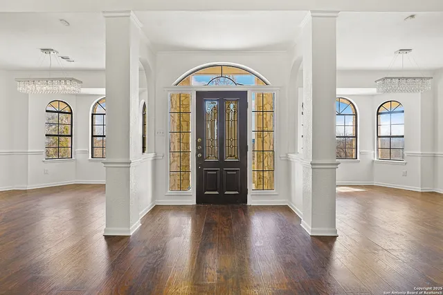 a view of an empty room with window and wooden floor