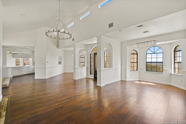 an empty room with wooden floor a fireplace and windows