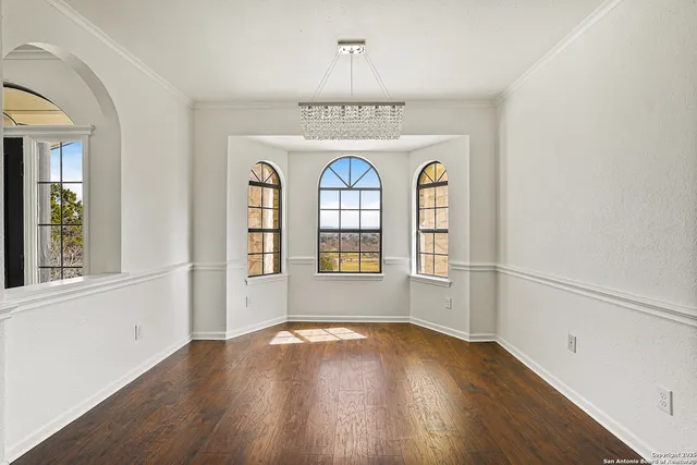 a view of an empty room with wooden floor fireplace and a window