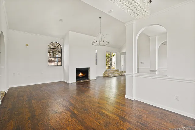 a view of an empty room with wooden floor fireplace and a window