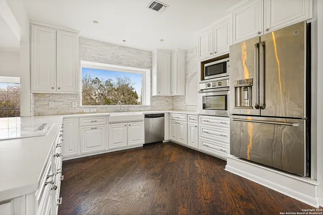a kitchen with granite countertop a refrigerator and a stove top oven
