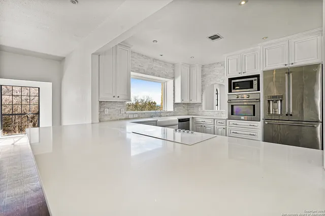 a view of an empty room with a kitchen and wooden floor