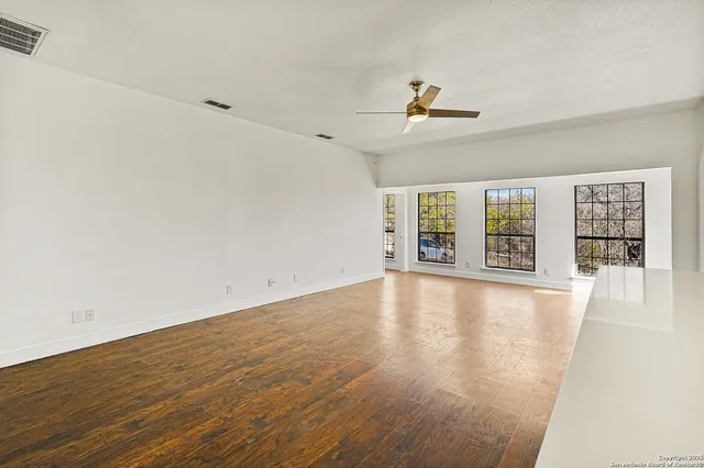 an empty room with wooden floor and windows