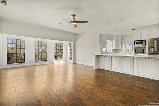 a view of an empty room with wooden floor and windows