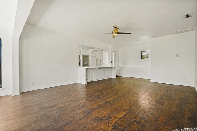 an empty room with wooden floor and fan