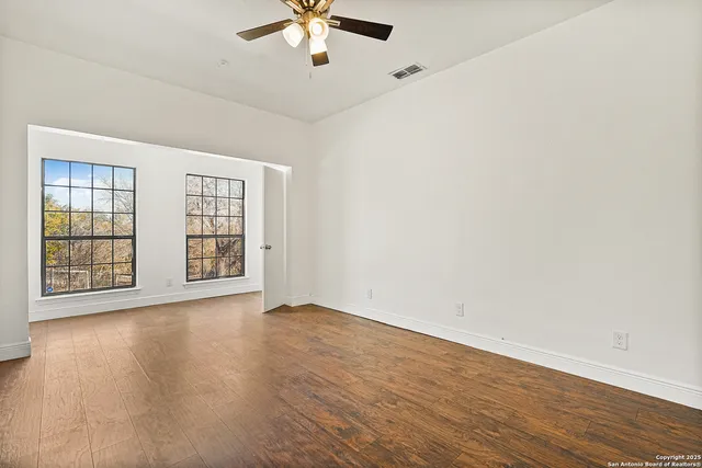 an empty room with fan and windows