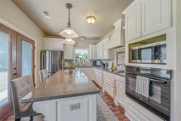 a kitchen with stainless steel appliances granite countertop a kitchen island a stove and a sink