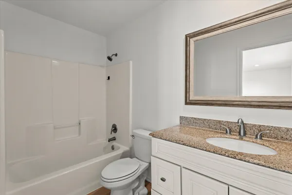 a bathroom with a granite countertop sink a toilet and a mirror