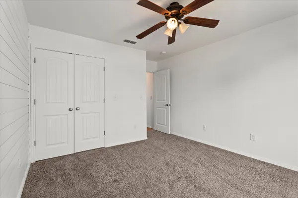 an empty room with closet and a chandelier fan