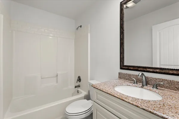 a bathroom with a granite countertop sink toilet a mirror and shower