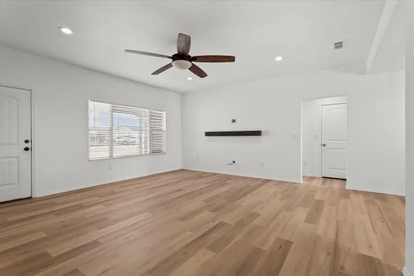 a view of empty room with wooden floor and fan