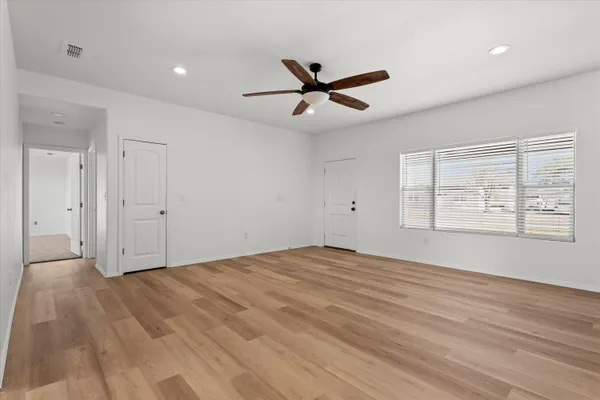 a view of an empty room with wooden floor and a window