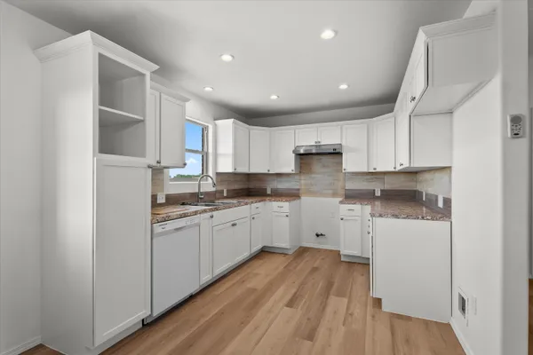 a kitchen with granite countertop white cabinets and white appliances