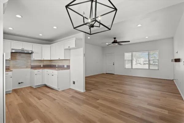 a kitchen with white cabinets and wooden floors