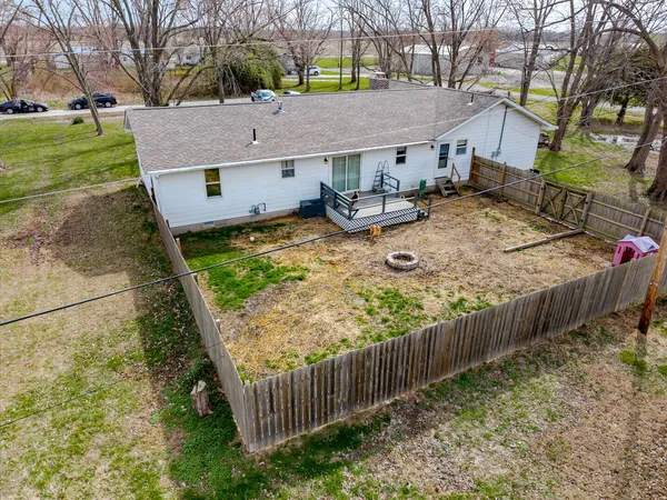 a view of a house with wooden fence next to a yard