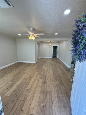 a view of empty room with wooden floor and fan