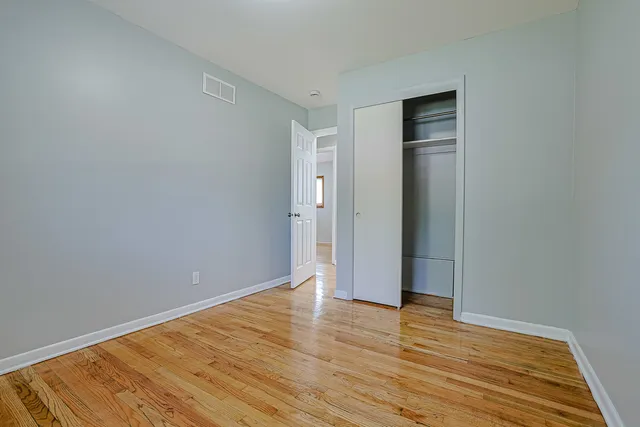 a view of an empty room with wooden floor and closet