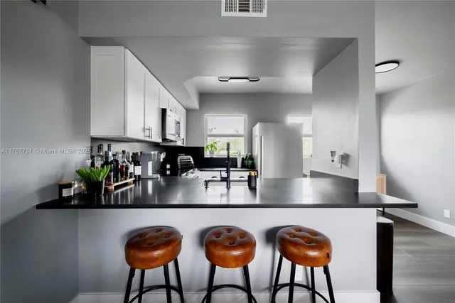 a kitchen with stainless steel appliances dining table a sink and cabinets