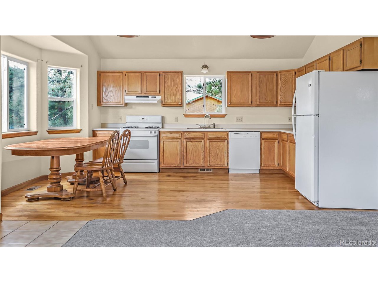 261 Wilkins Road Bailey, CO 80421 - Photo 5 of 39 a kitchen with a refrigerator a stove a dining table and chairs