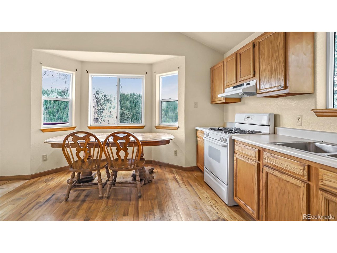 261 Wilkins Road Bailey, CO 80421 - Photo 6 of 39 a kitchen with stainless steel appliances kitchen island granite countertop a sink table and chairs