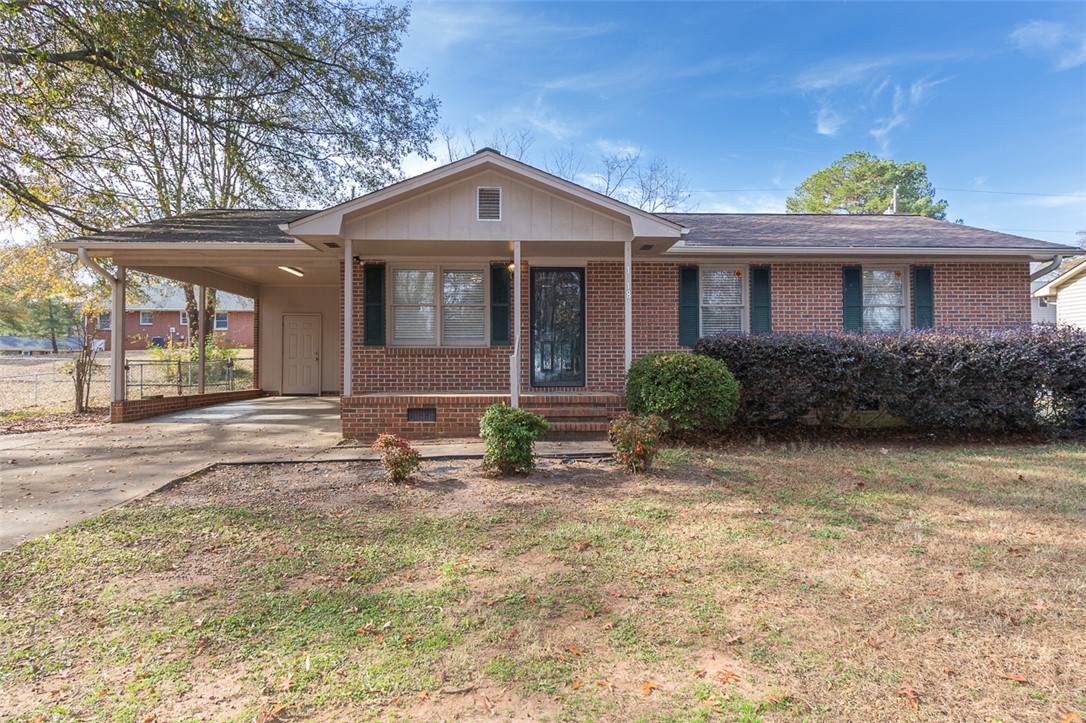 This classic brick residence features a welcoming carport and a manicured front yard.