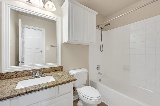 a bathroom with a granite countertop sink toilet and shower
